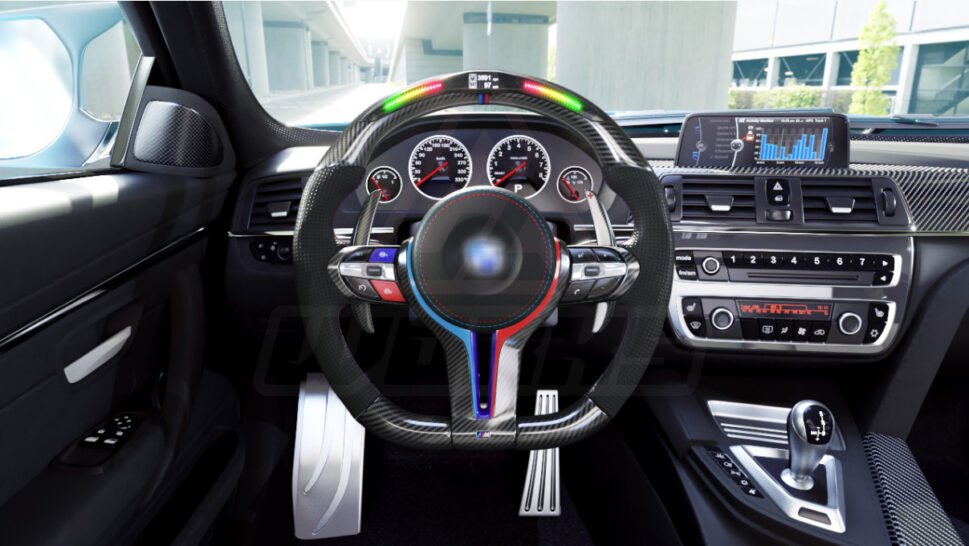 Front view of a BMW F chassis, M steering wheel in carbon fiber, extended paddle shifters, m color accents, black perforated leather, m color painted center trim, m color buttons, and led shift lights